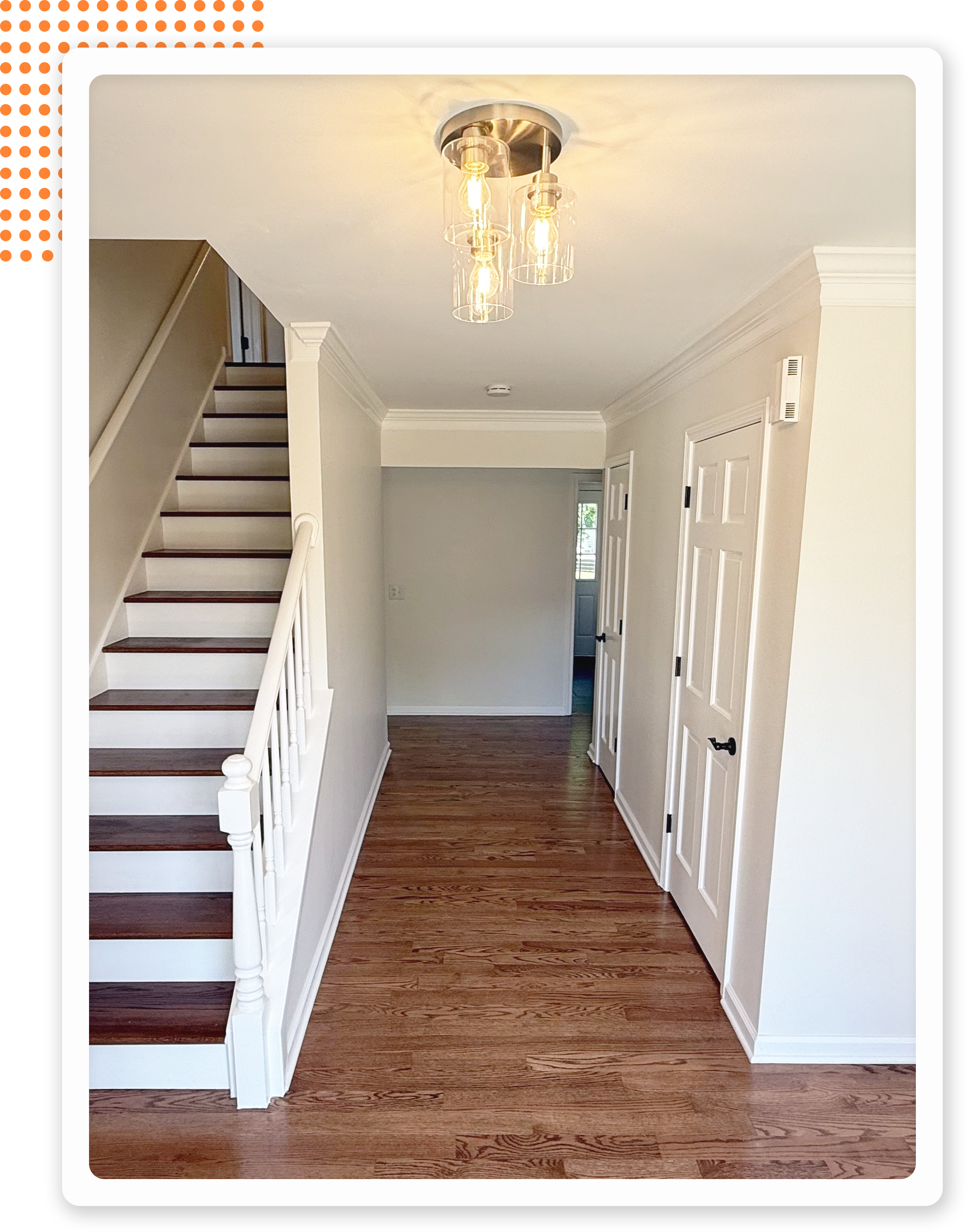 Bright hallway featuring wooden flooring, a staircase, and a modern light fixture with glass bulbs.